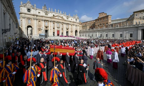Pope Francis's body is carried in a coffin across St Peter's Square; the cortege is escorted by Vatican guards in traditional red, blue and gold robes and cardinals in red and white; a large crowd stands behind.