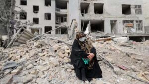 Rubble of destroyed residential buildings in Iran following US-Israeli strikes, with emergency workers searching for survivors amid widespread devastation affecting over 82,000 civilian structures