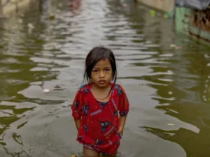 Pakistani children walking through floodwaters highlighting UNICEF climate change report impact on children