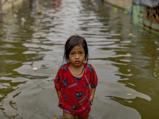 Pakistani children walking through floodwaters highlighting UNICEF climate change report impact on children